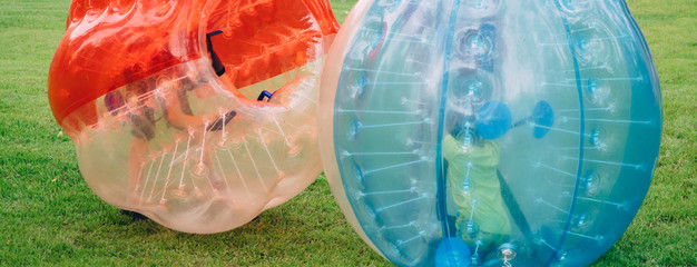 People play bumperball zorbsoccer outdoor. summer time
