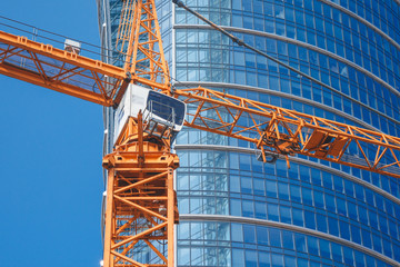 Pomarańczowy dźwig na tle drapacza chmur © Arsen