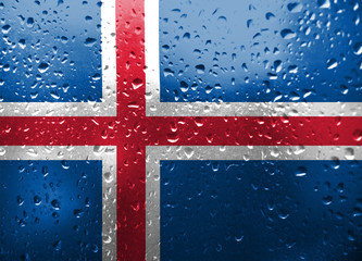 Texture of Iseland flag on the glass with drops of rain.
