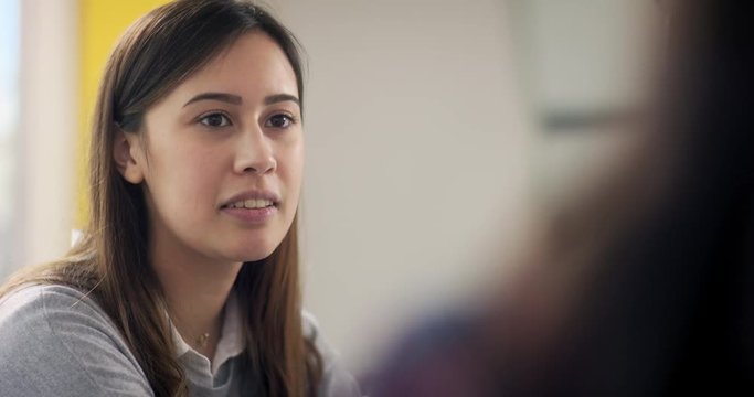 Close up shot of friendly black haired woman who smile and laugh to interlocutor