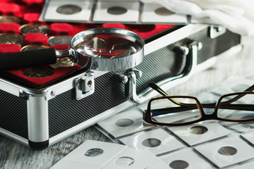 Different coins in the box for coins and a magnifying glass