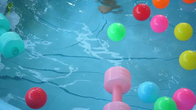 slow motion child playing water in baby inflatable pool with colorful ball floating