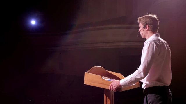 Speaker giving talk on podium at Business Conference. Entrepreneurship club. Person says about marketing and management for successful sales to college students indoors closeup. Professional ideas