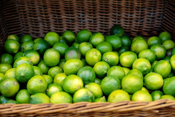 Fresh mature green limes in a wooden wicker basket in a store or supermarket or on the market