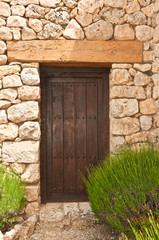 Front view, medium distance of an artisan build, oak door to a third generation winery with a hugh wood header in stone building in southeast Spain