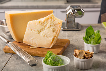 Parmesan cheese on cutting board with basil and knife on wooden background