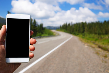 Mockup image of a man using smart phone with blank black screen on road