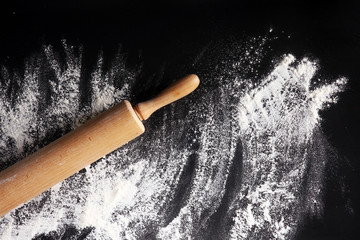 Baking background with the rolling pin with flour. On the dark table. Free space for text