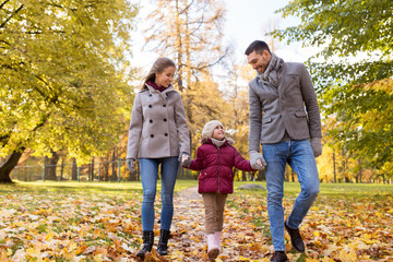 Fototapeta premium family, season and people concept - happy mother, father and little daughter walking at autumn park