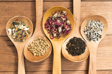 Wooden spoons with different herbs for infusion.