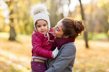 family, season and people concept - happy mother holding little daughter at autumn park
