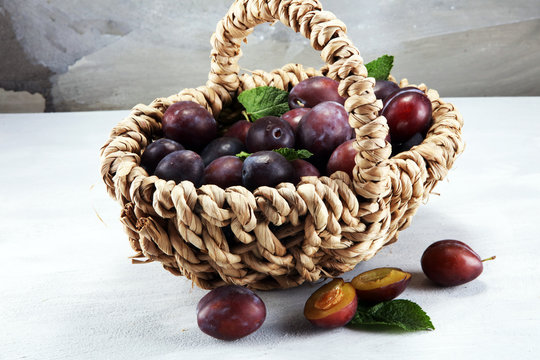 Plums on rustic stone background. Half of blue plum fruit. Many beautiful plums with leaves