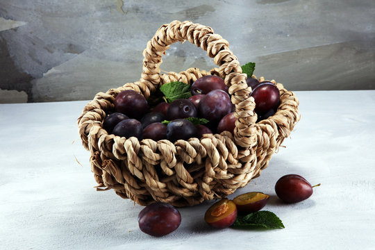 Plums on rustic stone background. Half of blue plum fruit. Many beautiful plums with leaves
