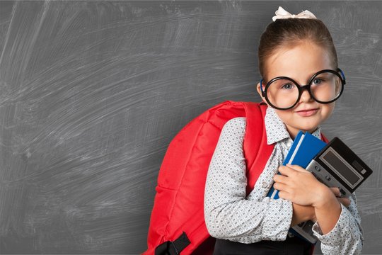 Little schoolgirl in glasses on blackboard