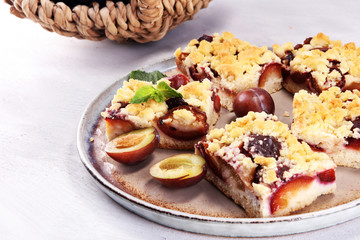 Rustic plum cake on wooden background with plums around.
