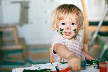 Portrait of adorable baby girl painting at home. © TY Studio