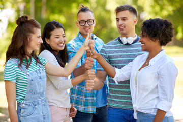 success, friendship and international concept - group of happy smiling friends making thumbs up gesture in park