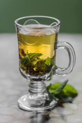 Cup with green tea and green leaves of mint