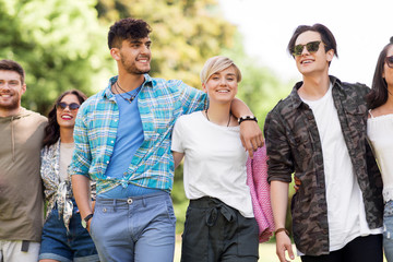 friendship and leisure concept - group of happy friends with picnic blanket at summer park