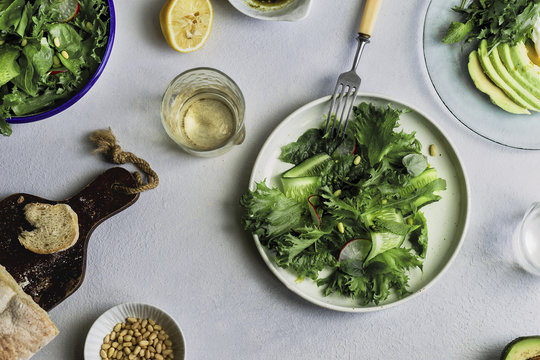Top view composition of healthy lunch with green salad plates, avocado and poached egg