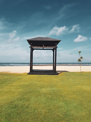 Wooden gazebo on the sandu beach against blue ocean and summer sky background