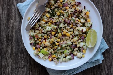 Delicious summer pasta salad on rustic table with corn, apple, red onion, cheese and dill