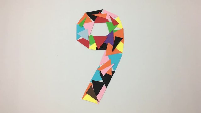 Numero nueve hecho de triangulos de colores se deshace por el viento.