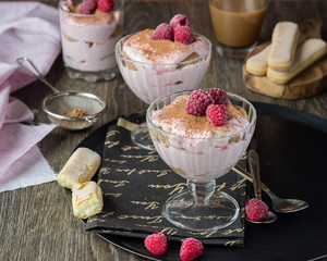 Italian dessert tiramisu with raspberries in a glass.