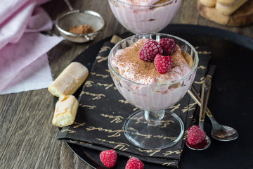 Italian dessert tiramisu with raspberries in a glass.