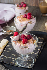 Italian dessert tiramisu with raspberries in a glass.