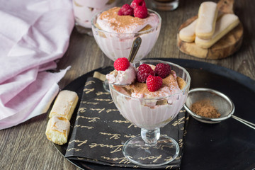 Italian dessert tiramisu with raspberries in a glass.
