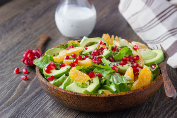 Superfood salad with avocado, tangerines, pomegranate and seeds with yogurt dressing.