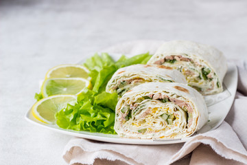 Tuna salad roll sandwich with salad leaves on white plate. Roll sandwich with tuna, cucumber, eggs and dill. Thin Armenian pita bread or lavash. Snack.