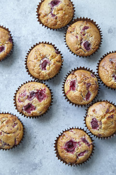 Raspberry and white chocolate muffins on light grey background