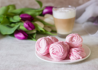 Pink homemade zephyr or marshmallow with cup of cappuccino coffee and flowers on light gray background. Marshmallow, Meringue, Zephyr