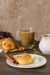 Homemade cinnamon buns rolls or cinnabons served with coffee on rustic table. Sweet traditional dessert for breakfast. Copy space.