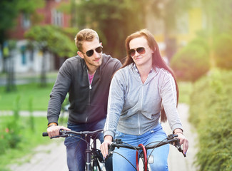 young couple riding bicycle together in a park