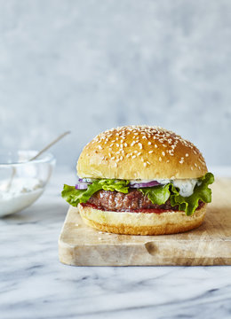 Lamb burger in brioche bun with mint yoghurt, served on a wooden board