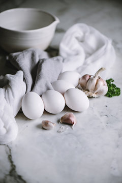 White eggs with garlic cloves on a marble worktop in a kitchen