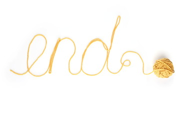 Word end made of yellow thread and thread ball isolated on white background. Cotton thread ball with word end.