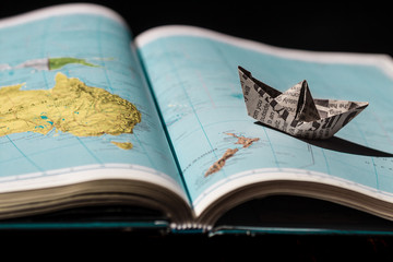Paper boat on the atlas of the world. The open book. Creative image. 