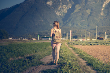 Junges Mädchen mit Rucksack geht auf Feldweg entlang