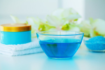 Organic Blue Sea Salt. Spa Composition With Cream, Salt, Towel and Flowers On a White Background. Wellness Products and Cosmetics