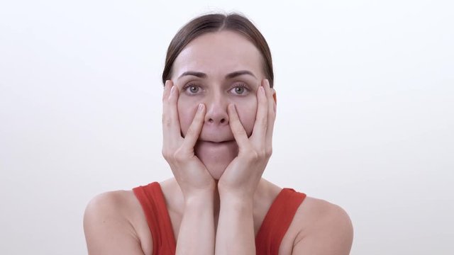 Portrait of smiling brunette girl doing exercise for strengthening the cheek muscles. Isolated on the white background.