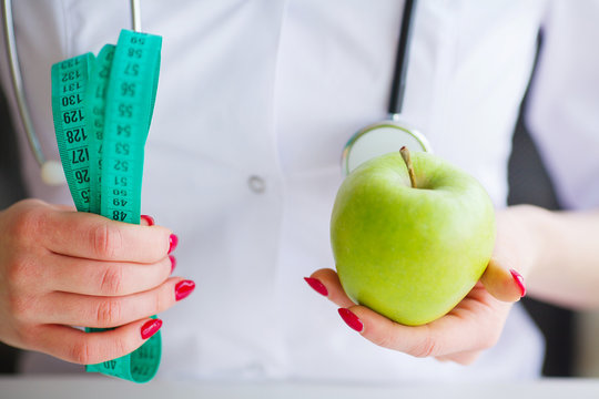 Diet. Fitness and healthy food diet concept. Balanced diet with vegetables. Portrait of cheerful doctor nutritionist measuring green apple in her office. Concept of natural food and healthy lifestyle
