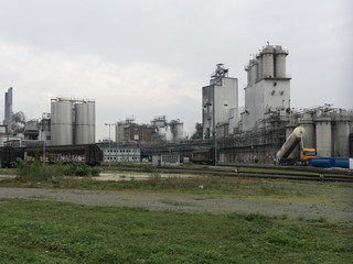 Large chemical factory in gray in cloudy weather with railway station