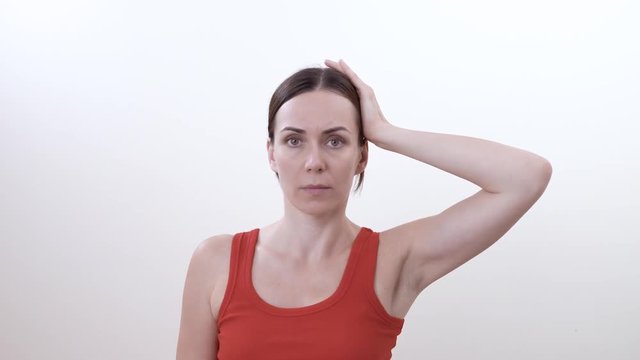 Portrait of a brunette woman doing strengthening exercise for left side muscles of the neck. Isolated on white background.