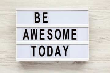 'Be awesome today' word on lightbox over white wooden background, from above. Closeup.
