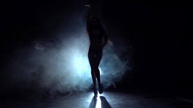 Girl dancing sexy dance . black smoke background. Silhouette. Slow motion