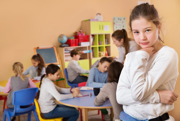 Upset girl in schoolroom on background with pupils